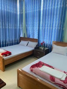 An Bình (1)MINH THU MOTEL的配有蓝色窗帘的客房内的两张床