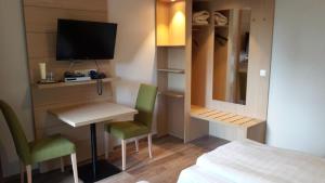 费尔登德尔海德克鲁格酒店的小房间设有床、书桌和电视