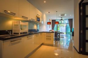 奈汉海滩Two Bedroom Onyx Villa Nai Harn的厨房配有白色橱柜、水槽和桌子