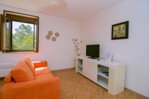 卡萨尔韦利诺Costiera del Cilento Apartments的客厅配有橙色椅子和电视