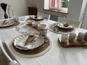 ArleufMaison au coeur du Morvan的一张带盘子和盘子的白色桌子