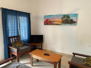 科洛里Queen Zee Garden Apartments的客厅配有桌子和墙上的绘画