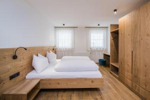 圣坎迪朵Kuenz Dolomites App 5的一间卧室设有两张床和木墙