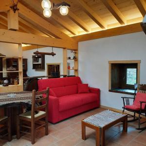 CasargoLa Casa nel Bosco - Your Mountain Holiday的一间带红色沙发的客厅和一间厨房