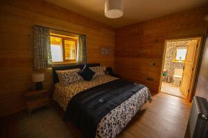 StoneLuxury Log Cabin with a Hot Tub的卧室配有一张床铺,位于带木墙的房间内