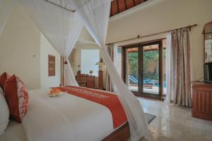沙努尔巴厘卡塔别墅度假村的卧室配有白色窗帘的床