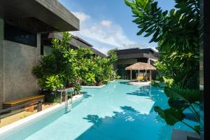 农布La Miniera Pool Villas Pattaya - SHA Plus的一座树木繁茂的建筑中间的游泳池