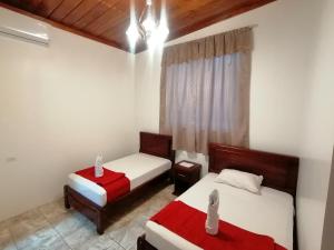 阿约拉港El Arco de Darwin的一间卧室配有两张红色和白色床单