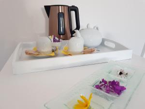 勒帕莱La Minoterie - Studio avec kitchenette et Chambre d'hôtes的白色的架子,上面有茶具和鲜花