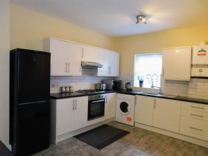 伦敦Entire 4 bedroom Terrace house in London的厨房配有白色橱柜和黑色冰箱。