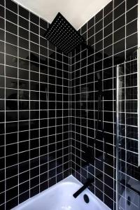 RoxburyArtist's Retreat In The Woods Five Acre Backyard的黑色瓷砖浴室设有浴缸和淋浴。