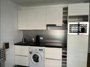德朗西Superbe studio lumineux haut de gamme tout confort的厨房配有白色橱柜和洗衣机。