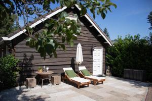 蒂尔堡Guesthouse "Mirabelle" met indoor jacuzzi, sauna & airco的庭院配有两把椅子、一张桌子和一把遮阳伞