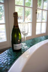 蒂尔堡Guesthouse "Mirabelle" met indoor jacuzzi, sauna & airco的一张桌子上坐着一瓶葡萄酒和一杯