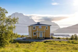 StoreidetPederStua, a classic fisherman's farm house in the middle of Lofoten的山丘上的黄色房子,背景是群山