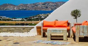 帕罗斯岛Villa Mira Paros - Luxury Suites的庭院配有橙色沙发和桌子