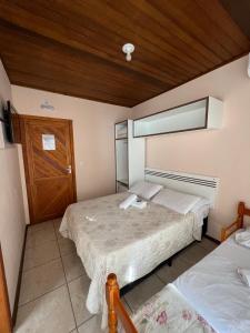 佩尼亚Pousada Rosália的一间卧室设有两张床和木制天花板