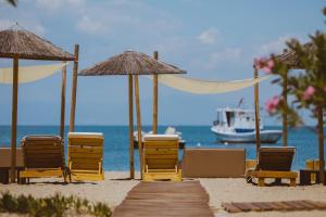 普利瑙港湾Elektra Comfort Hotel的海滩上的一组椅子和遮阳伞