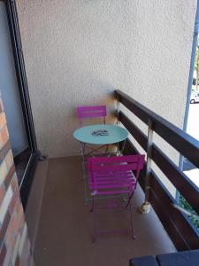 卡布尔Le petit Cabourgeais的阳台配有2把紫色椅子和1张桌子