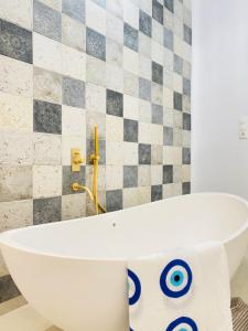 阿斯提帕莱亚镇Gerani Deluxe Houses的浴室设有白色浴缸,浴室设有瓷砖墙
