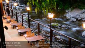 伊豆龙田日式旅馆的享有河流美景,配有桌子和灯