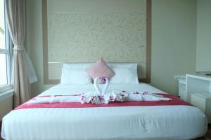 芭堤雅市中心芭堤雅海滨度假酒店的一张白色的床,上面有粉红色的枕头和鲜花