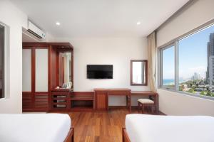 岘港岘港公河大酒店的一间卧室配有书桌、电视和窗户。