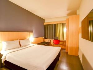 里约热内卢宜必思RJ新星美国酒店的一间卧室配有一张大床和一张红色椅子