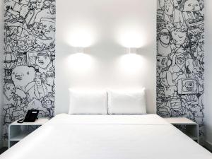 阿拉戈伊尼亚斯ibis Styles Alagoinhas的卧室配有白色的床和带壁画的墙壁