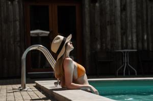 YasnogorodkaEden Resort的坐在游泳池旁的戴帽子的女人