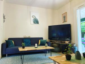 比亚里茨Villa de charme parc fleuri, arboré et piscine à BIARRITZ的客厅配有蓝色的沙发和电视