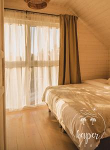 韦巴Kaper Łeba - Domki Nad Morzem的一间卧室配有床和带窗帘的窗户