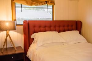什鲁斯伯里Hencote Vineyard Glamping Village的一张带红色床头板和窗户的床