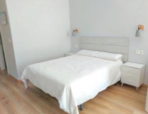多列毛利诺斯拉诺加乐拉公寓的一间白色卧室,配有床和床头柜
