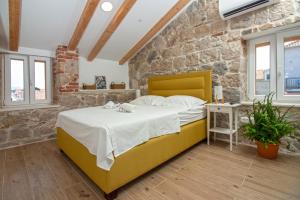 斯普利特Maki Stone House - Parking on request !的一间石墙内带黄色床的卧室