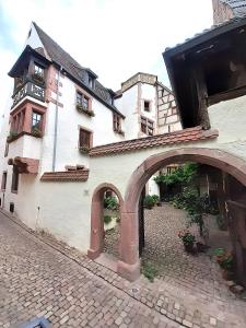 利克维ADRIHOF à Riquewihr, Cour de l'Abbaye d'Autrey的街道上一座带拱门的大型白色建筑