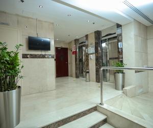 沙迦Al Sharq Hotel Suites - BAITHANS的大堂设有楼梯和墙上的电视。