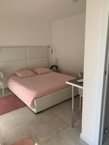 昂蒂布Villa Elimia avec piscine chauffée的一间卧室配有一张带粉色床单和一张桌子的床。