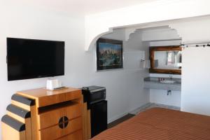 加迪纳市埃多拉多汽车旅馆的一间卧室配有一张床、一台电视和一个梳妆台