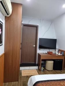 Cao LãnhHotel Trí Lê的一间卧室设有木门和一张书桌及电视