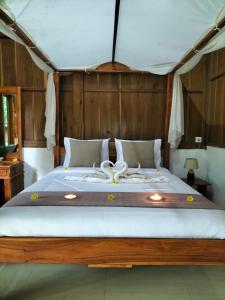 新加拉惹Friendly Homestay Lemukih的一间卧室配有一张大床和木制床头板