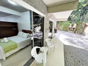 邦比尼亚斯Refúgio da Lagoinha - Centro de Bombinhas的一间卧室配有一张床和两把椅子,并设有一个阳台