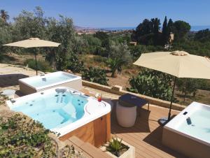 阿格里真托Villa La Lumia B&B Suites & Apartments的甲板上的热水浴池配有遮阳伞