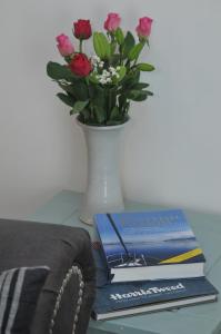 斯托诺韦No5 Esplanade Court, Stornoway Town Centre的一张带花瓶的桌子,上面有书和鲜花