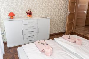 代姆延Ruben Vendégház的卧室配有白色梳妆台和床上的粉红色拖鞋