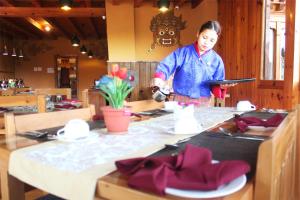 帕罗Rema Resort的一位在餐厅餐桌上准备食物的女人