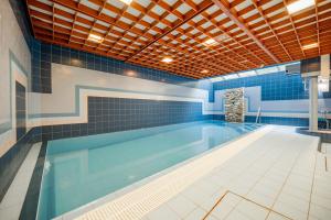 赫拉德茨 - 克拉洛韦乌克拉罗伟伊利斯基酒店的蓝色瓷砖游泳池和大型游泳池