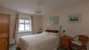 巴利卡斯尔Strand Cottages Ballycastle Seafront的一间卧室设有一张床、一个窗口和一把椅子