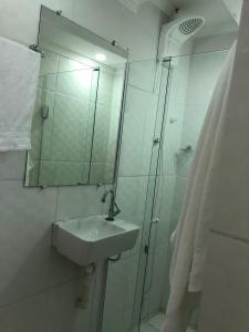瓜鲁柳斯Lá Casa do Manguinha的浴室配有盥洗盆和带镜子的淋浴