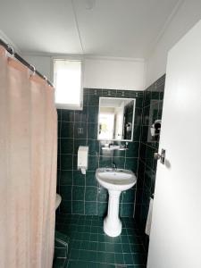 古尔本Hillview Motel的绿色瓷砖浴室设有水槽和镜子